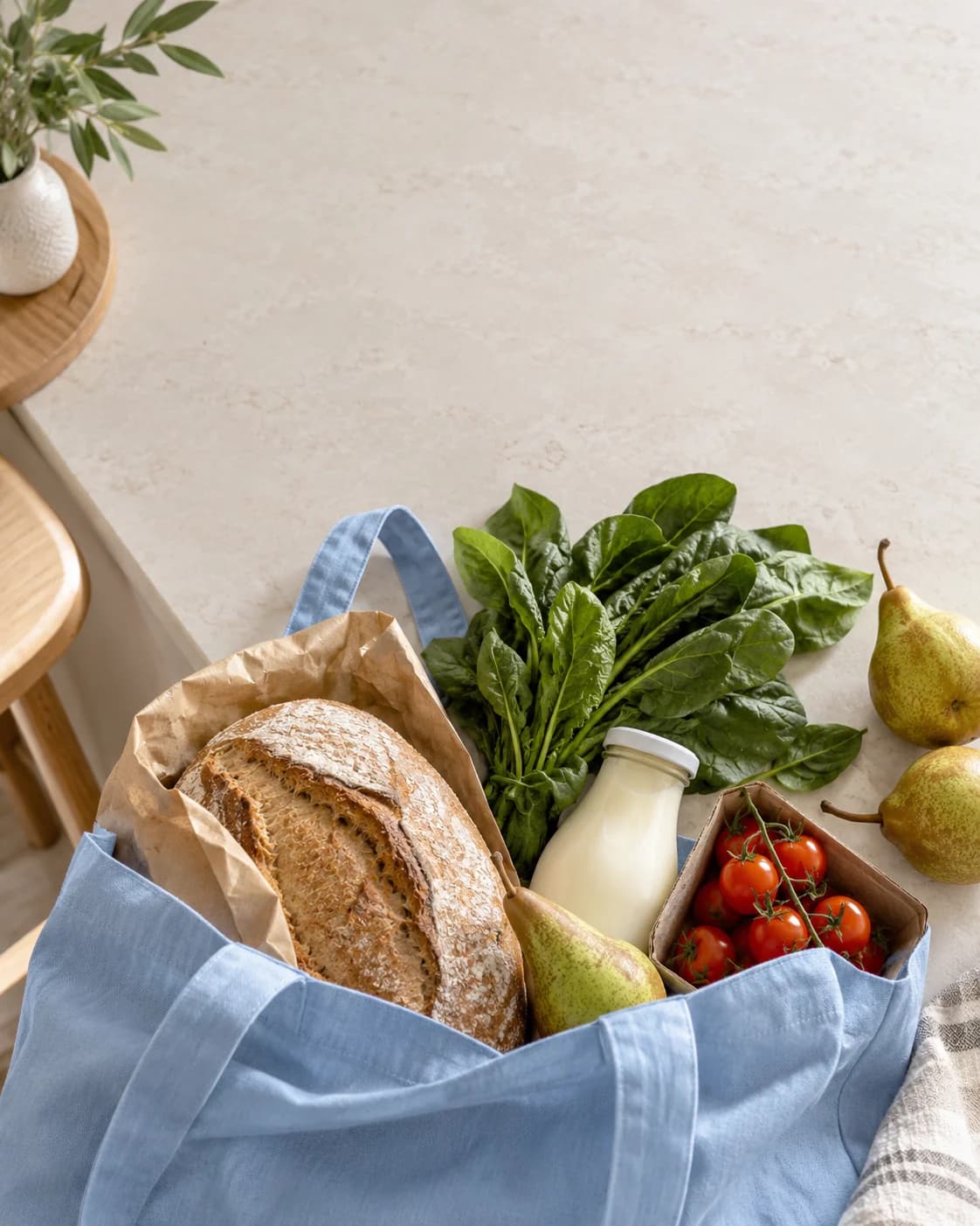 A blue shopping tote and fresh groceries on a pale kitchen island